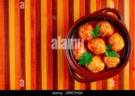 Deftige Fleischbällchen in Tomatensauce, serviert in einer Schüssel auf hölzernem Hintergrund Stockfoto