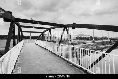 Ein Schwarzweißbild, das über eine Fußgängerbrücke über den Leeds Liverpool Canal in Richtung des DW Stadium in Wigan blickt, gesehen im September 2023. Stockfoto