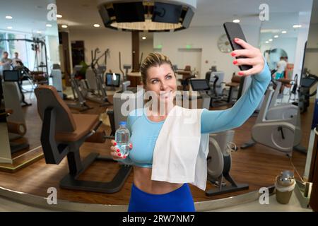 Attraktive Sportfrauen trinken Wasser und machen Selfie auf dem Smartphone Stockfoto
