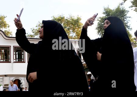 Muslimische Frauen, jede mit einer Burka, nehmen Selfies mit ihren Smartphones in der Eyüp Sultan Moschee in Istanbul, Türkei Stockfoto
