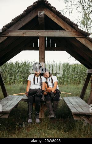 Porträt von Mädchen Jockeys, die auf einem Holztisch unter einem Baldachin sitzen. Stockfoto