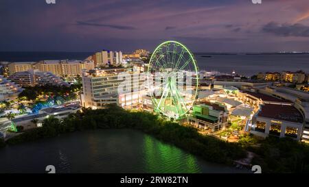 Erleben Sie den atemberaubenden Blick auf die Hotelzone von Cancún bei Nacht. Die lebhaften Lichter von Touristenläden und Restaurants beleuchten die Szene, perfekt CO Stockfoto