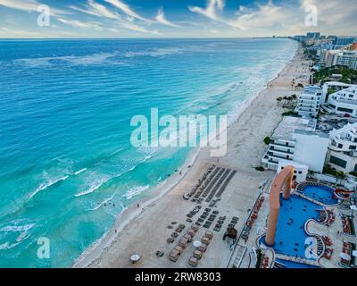 Genießen Sie das lebhafte Tageslicht-Panorama der unberührten Strände von Cancún. Das türkisfarbene Wasser der Karibik überspült den weißen Sand, während die Strandurlauber Ba Stockfoto