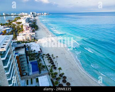 Genießen Sie das lebhafte Tageslicht-Panorama der unberührten Strände von Cancún. Das türkisfarbene Wasser der Karibik überspült den weißen Sand, während die Strandurlauber Ba Stockfoto