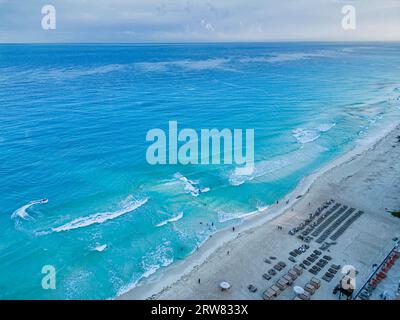 Genießen Sie das lebhafte Tageslicht-Panorama der unberührten Strände von Cancún. Das türkisfarbene Wasser der Karibik überspült den weißen Sand, während die Strandurlauber Ba Stockfoto