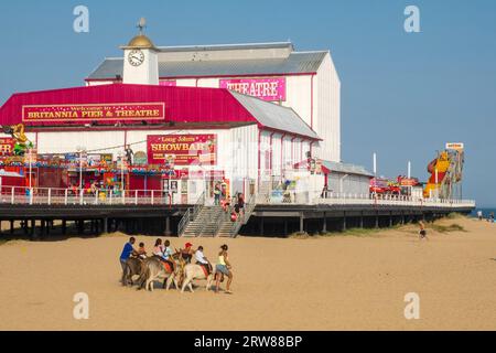 Großartiger Yarmouth Beach, Norfolk, Großbritannien. Eselsfahrten mit dem Britannia Pier und dem Theater dahinter. Stockfoto