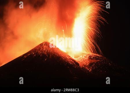 Ätna-Vulkan in Sizilien - Blick auf den Krater während einer gigantischen Lavaexplosion in der Nacht mit suggestivem Licht und Hintergrundlicht Silhouette des aktiven obersten Kraters Stockfoto