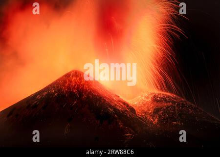 Ätna-Vulkan in Sizilien - Blick auf den Krater während einer gigantischen Lavaexplosion in der Nacht mit suggestivem Licht und Hintergrundlicht Silhouette des aktiven obersten Kraters Stockfoto