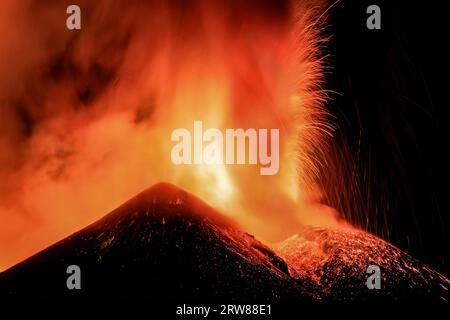 Ätna-Vulkan in Sizilien - Blick auf den Krater während einer gigantischen Lavaexplosion in der Nacht mit suggestivem Licht und Hintergrundlicht Silhouette des aktiven obersten Kraters Stockfoto