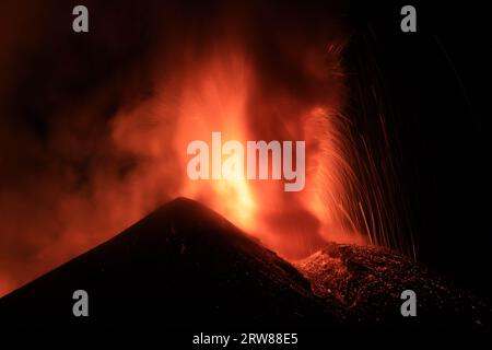 Ätna-Vulkan in Sizilien - Blick auf den Krater während einer gigantischen Lavaexplosion in der Nacht mit suggestivem Licht und Hintergrundlicht Silhouette des aktiven obersten Kraters Stockfoto