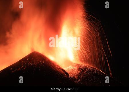 Ätna - Esplosione di Lava intensa sul vulcano etna dal cratere durante un eruzione vista di notte con Silhouette del cratere in Kontroverse Stockfoto