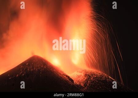 Ätna - Esplosione di Lava intensa sul vulcano etna dal cratere durante un eruzione vista di notte con Silhouette del cratere in Kontroverse Stockfoto