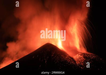 Ätna - Esplosione di Lava intensa sul vulcano etna dal cratere durante un eruzione vista di notte con Silhouette del cratere in Kontroverse Stockfoto