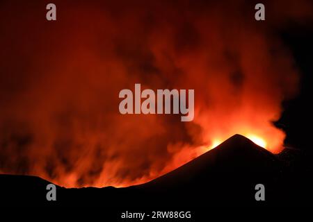 Ätna in einem nächtlichen Lavaausbruch mit hinterleuchteten Silhouettenkrater und großen Rauchemissionen in einem Panoramablick auf den Vulkan sizilien Stockfoto