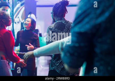 Die Leute tanzen im Nachtclub, während sie an einer Diskothek teilnehmen und das Nachtleben genießen. Die Zuschauer haben Spaß und bewegen sich zu Musik-Beats auf der Tanzfläche im Club Stockfoto
