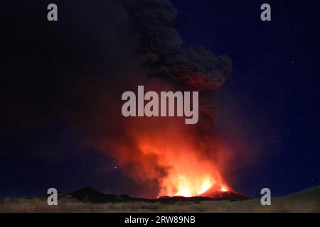 Ätna eruzione in Sicilia con vista panoramica della grande colonna di fumo e cenere dal cratere vulcano nel ciel notturno stellato del Agosto 2023 Stockfoto