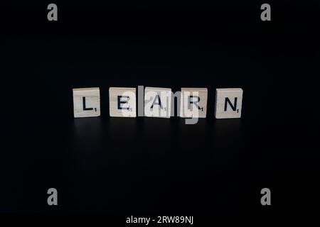 Lake Elsinore, CA, USA – 17. September 2023: Scrabble-Fliesen isoliert auf schwarzem Hintergrund, die das Wort lernen beschreiben. Stockfoto