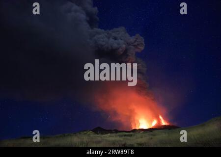 Ätna eruzione in Sicilia con vista panoramica della grande colonna di fumo e cenere dal cratere vulcano nel ciel notturno stellato del Agosto 2023 Stockfoto