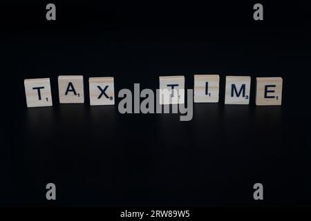 Lake Elsinore, CA, USA - 17. September 2023: Scrabble-Fliesen isoliert auf schwarzem Hintergrund, die die Aufenthaltswörter der Steuerzeit beschreiben. Stockfoto