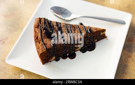 Süßes, zartes dreieckiges Stück Schokoladen-Nuss-Kuchen, mit flüssiger Schokolade gefüllt, auf Teller serviert Stockfoto