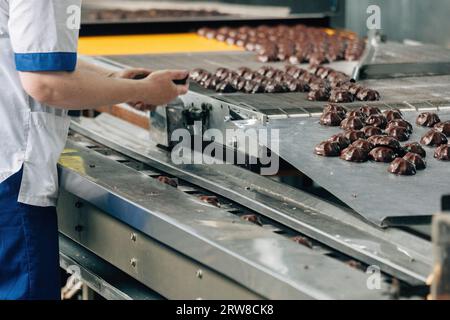 Süßwarenarbeiter, der Marshmallows auf Förderband sortiert. Stockfoto