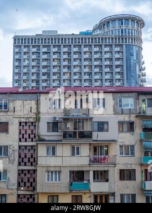 Batumi-Architekturkonzept. Altes Haus vor dem Hintergrund eines neuen Hochhauses. Kontrast in der Architektur. Wohnraum für Menschen. Balkone und W Stockfoto