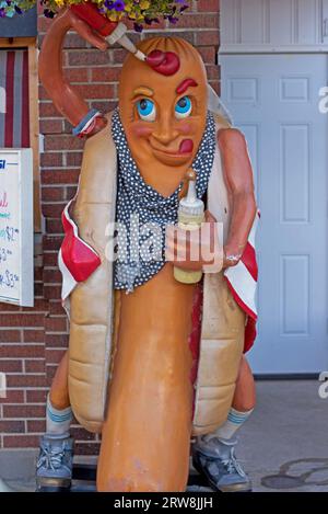 Eine skurrile Statue zeigt einen Hot Dog, der mit einer amerikanischen Flagge geschmückt ist und sich eifrig auf den Verzehr vorbereitet. Stockfoto