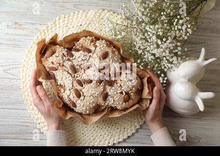 Frau mit köstlichem italienischen Oster-Taubenkuchen (traditionelles Colomba di Pasqua) am weißen Holztisch, Blick von oben Stockfoto