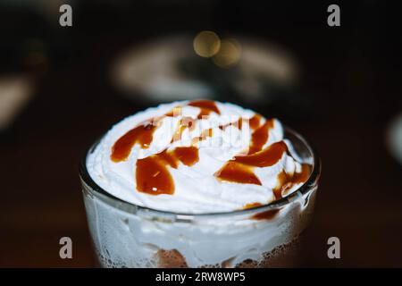 Schokolade mit Schlagsahne und Karamellsauce in einem Glas mit Bokeh-Hintergrund Stockfoto