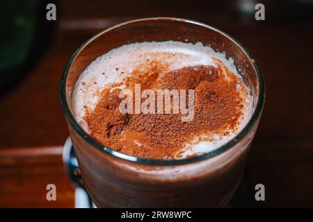 Milch mit Schokolade oder Kakaopulver auf der Oberseite in einem Glas mit Bokeh-Hintergrund Stockfoto