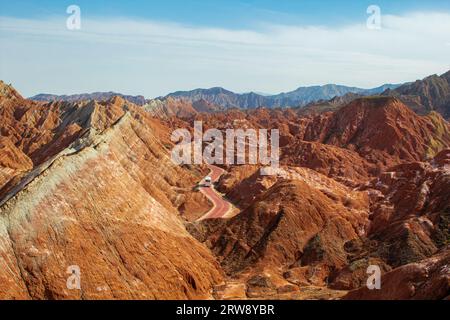 Kurvige Straße durch die bunten Regenbogenberge. Die chinesische Landschaft auf der Seidenstraße. Wunderschöner Sonnenuntergang im Zhangye Danxia National Geological Park, Gan Stockfoto