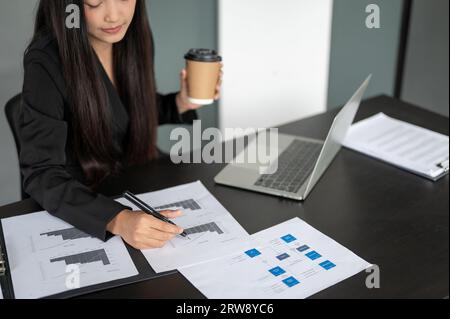 Abgeschnittenes Bild einer fokussierten und professionellen asiatischen Geschäftsfrau oder Finanzassistentin, die an Finanzdatenberichten arbeitet und das Finale analysiert Stockfoto