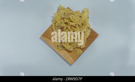 Kacang rempeyek oder peyek. Cracker aus Erdnüssen gemischt mit Reismehlmischung, die gebraten werden. Serviert auf einem Holzteller. Isoliert auf weißem Hintergrund Stockfoto