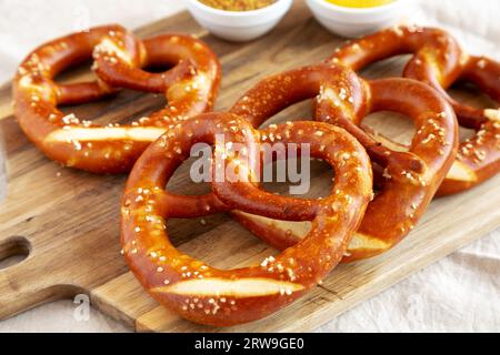 Hausgemachte weiche bayerische Brezeln mit Senf auf Holzbrett, Seitenansicht. Stockfoto