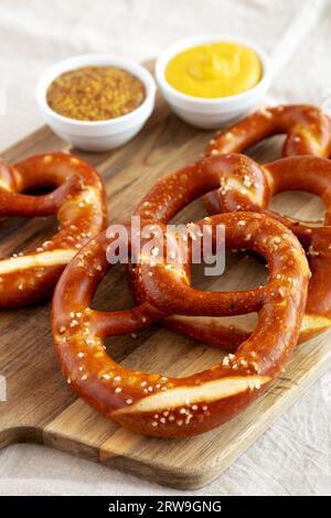 Hausgemachte weiche bayerische Brezeln mit Senf auf Holzbrett, Seitenansicht. Stockfoto