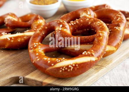 Hausgemachte weiche bayerische Brezeln mit Senf auf Holzbrett, Seitenansicht. Stockfoto