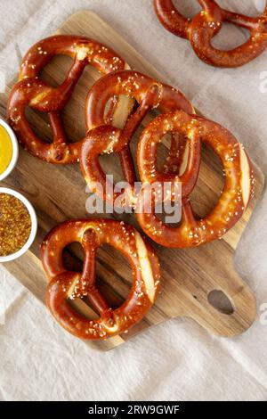 Hausgemachte weiche bayerische Brezeln mit Senf auf Holzbrett, Blick von oben. Stockfoto