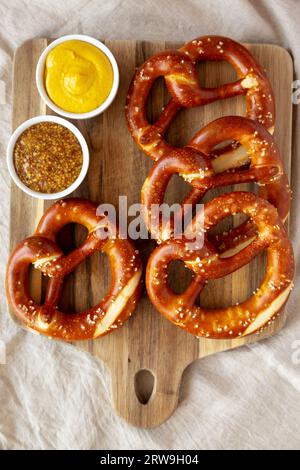 Hausgemachte weiche bayerische Brezeln mit Senf auf Holzbrett, Blick von oben. Stockfoto