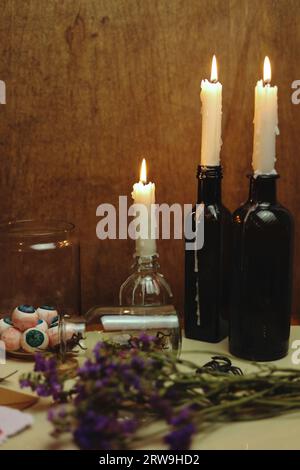 halloween Stillleben mit brennenden Kerzen und Augenbrauen in einem Glas Stockfoto