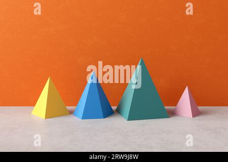 Dreidimensionale Prisma-Pyramidenobjekte auf orangefarbenem oder gelbem Hintergrund. Geometrische Figuren Stilllebenzusammensetzung. Einfachheit und Harmonie Stockfoto