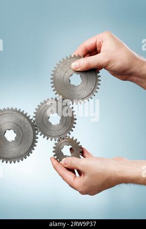 Mann, der ein mechanisches System mit alten Zahnrädern aus Metall entwirft Stockfoto