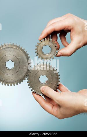 Mann, der ein mechanisches System mit alten Zahnrädern konstruiert Stockfoto