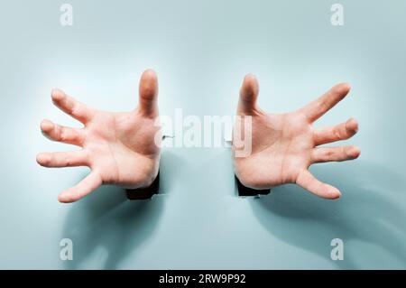 Seltsame Hände kommen durch Löcher in einem blauen Karton Stockfoto