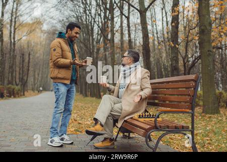 Multikulturelle Freundschaft von Menschen unterschiedlichen Alters. Ein Treffen von zwei Freunden für ein Schachspiel im Park. Stockfoto