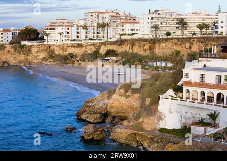 Kleiner ruhiger Strand umgeben von Klippen und Apartmenthäusern im malerischen Ferienort Nerja an der Costa del Sol, Andalusien, Südspanien Stockfoto