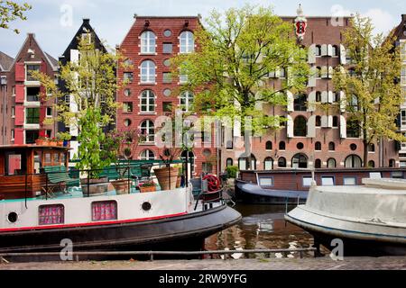 Hausboote und alte Lagerhäuser, die in Wohnblocks entlang der Brouwersgracht in Amsterdam, Niederlande, Nordholland umgebaut wurden Stockfoto