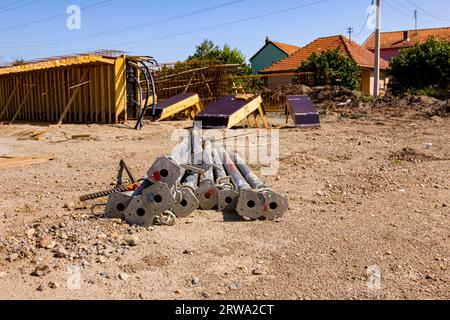 Stapel aus Metallsäulen für Betonierarbeiten, die im Hintergrund auf der Baustelle zur aufrechten Stützung im Bauwesen und im Ingenieurwesen auf dem Boden platziert werden Stockfoto