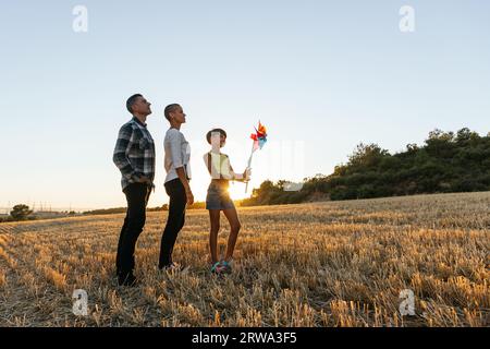 Mom, Dad und Tochter haben Spaß auf dem Feld bei Sonnenuntergang. Stockfoto