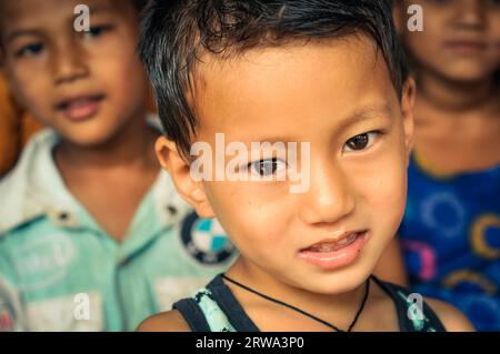 Damak, Nepal, um Mai 2012: Foto eines Jungen mit schönen braunen Augen, der auf eine Fotokamera im nepalesischen Flüchtlingscamp in Damak, Nepal, schaut. Dokumentarfilm Stockfoto