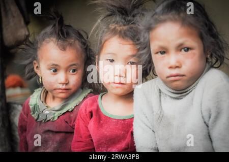 Dolpo, Nepal, um Mai 2012: Foto von drei jungen braunhaarigen und braunäugigen Mädchen in Dolpo, Nepal. Zwei Mädchen tragen ein pinkfarbenes Hemd und eines weiß Stockfoto